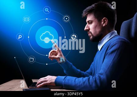 Young man using laptop for cloud computing in a dark room Stock Photo