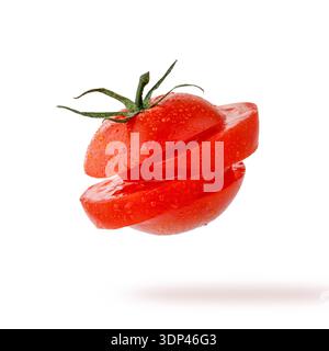 Sliced single ripe juicy red tomato with water drops closeup flying on white background Stock Photo