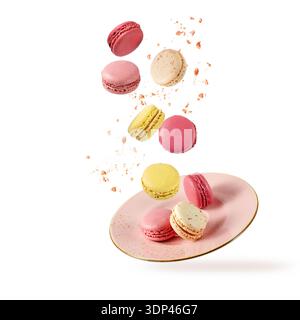 French sweet colorful fruit cookies macarons macaroons with crumbs flying falling on vintage pink plate isolated  on white background. Pastry shop car Stock Photo