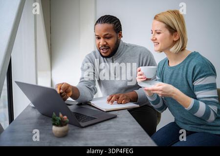 Diverse colleagues collaborating on laptop in modern office space Stock Photo
