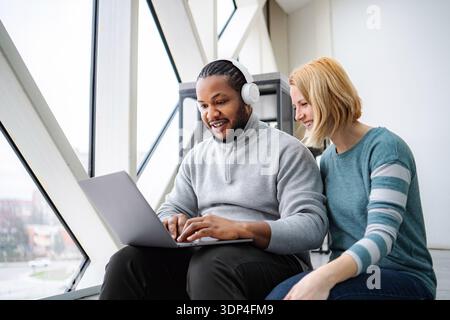 Diverse colleagues collaborating on laptop in creative office Stock Photo