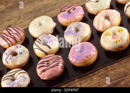 Mini donuts covered in chocolate on a black background. Stock Photo