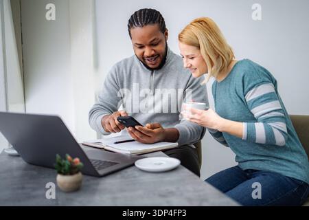 Diverse couple discussing content on smartphone at home Stock Photo
