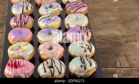 Mini donuts covered in chocolate on a black background. Stock Photo