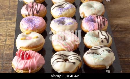 Mini donuts covered in chocolate on a black background. Stock Photo
