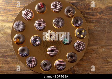 Mini donuts covered in dark chocolate on a gold background. Stock Photo