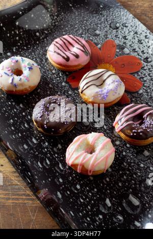 Chocolate glazed mini donuts on black plate close-up Stock Photo
