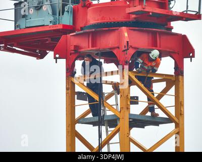 Construction Workers On Crane Tower Inspecting Structure With Safety Gear And Teamwork At Height Stock Photo