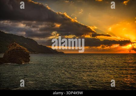 Corsica Dramatic Sunset Over Mediterranean!  This color photograph emphasizes contrast between dark clouds and golden light over the sea, creating a p Stock Photo