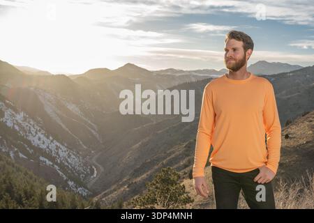 Pensive man standing in a vast mountain landscape at sunset Stock Photo