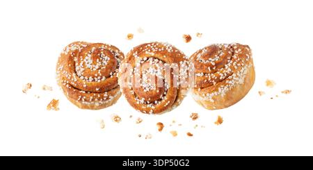 Fresh baked three cinnamon buns with crumbs flying isolated on white background. Traditional swedish sweet pastry kanelbulle. Group of sweet buns. Stock Photo