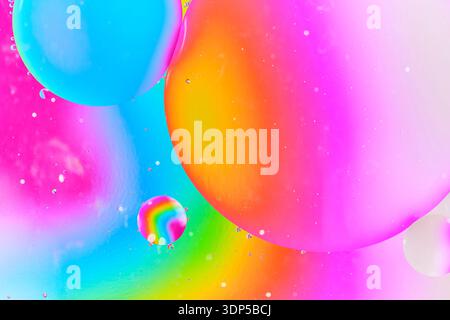 Abstract liquid art showing large overlapping oil bubbles with focus on warm orange and pink glow contrasted by cool blue tones Stock Photo