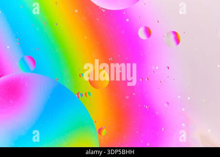 Minimalist abstract macro showing small, delicate oil droplets scattered across soft rainbow gradient background Stock Photo