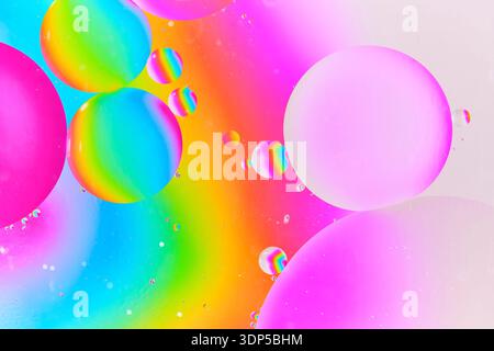 Artistic macro composition various sized oil droplets floating over vibrant spectrum neon colors, creating bokeh like effect Stock Photo