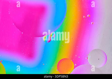 Vibrant macro photography of oil drops in water. Abstract background featuring neon pink, blue, and green gradient circles Stock Photo