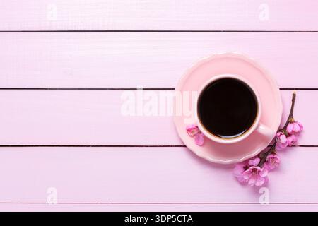 Cup of coffee and blossoming branch of Peach  on pink wooden table. Top view with copy space. Flat lay Stock Photo