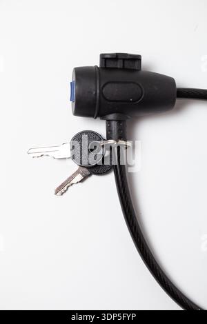 Black cable lock with attached keys for securing bicycles, luggage, and personal items, ideal for travel and everyday security. Stock Photo