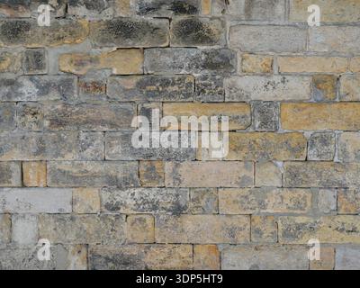 Historic stone facade with irregularly hewn yellow-black ashlars and visible patina. Copyspace. Stock Photo