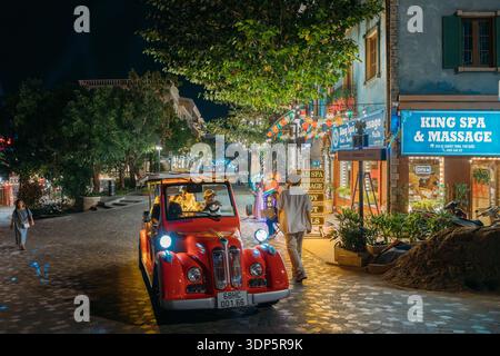 Red vintage electric tourist car moving fast on night street in Phu Quoc Stock Photo