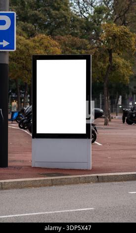 Blank advertising billboard mockup standing on city street next to parking area Stock Photo