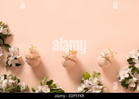 Decorative Easter eggs with spring blossom branches on pastel pink background with copy space. Minimal seasonal holiday composition. Stock Photo