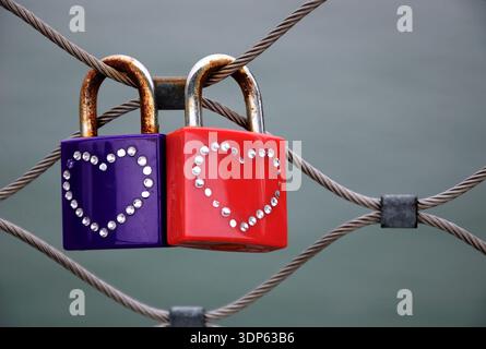 Two grungy love padlocks with heart decoration attached to the bridge in Paris. Valentine's day background. Stock Photo