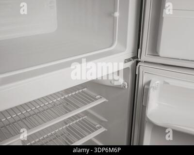 Empty refrigerator and freezer interior with open door, white shelves and storage compartments. Clean modern kitchen appliance, cold storage concept w Stock Photo