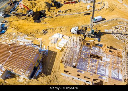 Workers are busy building new beams framing structures at construction site with trucks cranes Stock Photo