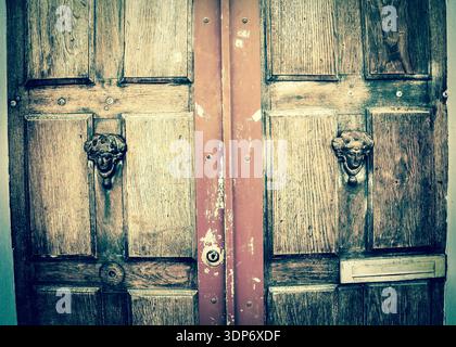 Antique doors. Weathered wooden old door with decorative handles - in shape of human head with wreath on it (like Roman patrician). Paris, France. Ret Stock Photo