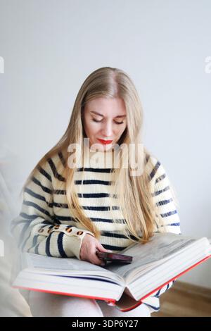woman presenting open hardcover book. Learning, studying and literature concept in soft natural light. Stock Photo