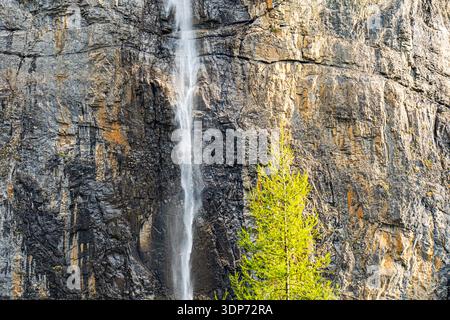 Tall waterfall cascading down a rocky mountain cliff Stock Photo