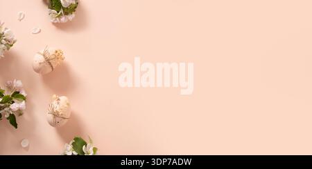 Easter banner with pink eggs with spring blossom branches on pastel pink background with copy space. Minimal seasonal holiday composition. Stock Photo