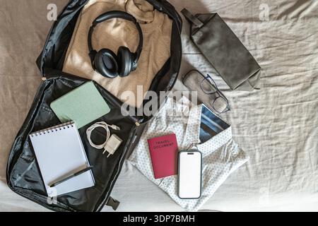 Flat lay of travel essentials prepared for short trip in warm natural light. Digital lifestyle and mobility concept. Stock Photo