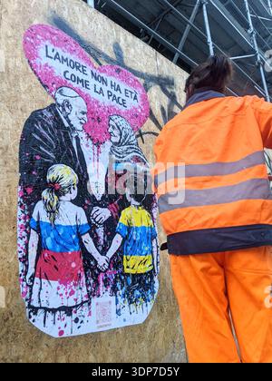 Milan, love is as ageless as peace. A work by CDonati Meyer for a peaceful Valentine's Day. For Valentine's Day, a street art project that combines visual language and civic engagement in a universal message. Created in graffiti style with a palette of fuchsia, black, and white, the work depicts an elderly couple-an Israeli man and a Palestinian woman-holding hands beneath a large heart covered in drippings and splashes of color. In front of them, two children-a girl in the colors of Russia and a boy in those of Ukraine-also hold hands. Stock Photo