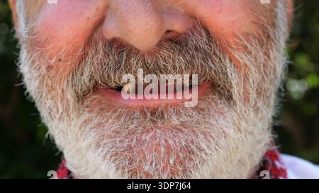 Close up toothless mouth of older bearded man smiling on camera. His expression open and kind, showing the warmth and simplicity of genuine emotion Stock Photo