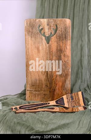 Rustic Wooden Cutting Board with Deer Motif and Utensils Stock Photo