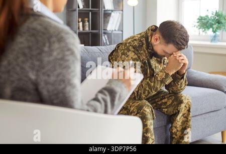 Woman psychologist talking to young depressed soldier in clinic Stock Photo