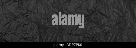 Black crumpled paper showing abstract wrinkles and creases for a textured background Stock Photo