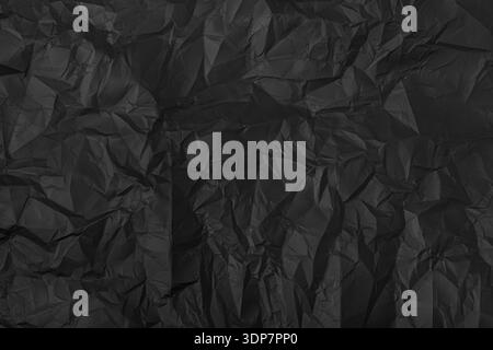 Black crumpled paper creating a textured surface with abstract shadows and creases Stock Photo