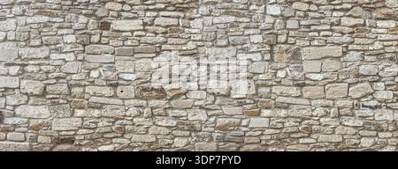Rough stone wall background featuring natural texture and ancient masonry construction Stock Photo