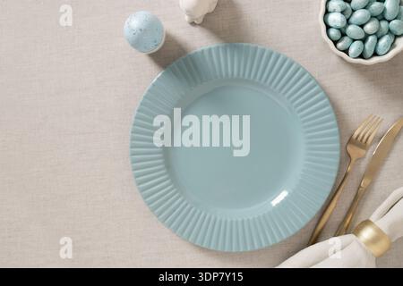 Elegant Easter table arrangement with ceramic plate, linen napkin, decorative eggs and willow branches creating festive spring atmosphere. Stock Photo
