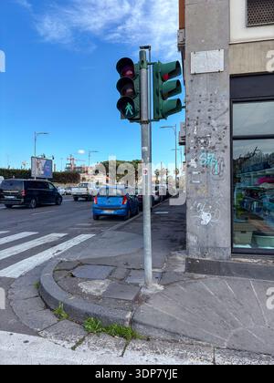 Pedestrian traffic light showing green man signal at a crosswalk. Traffic control device, walk light, urban infrastructure in Catania, Italy. Stock Photo