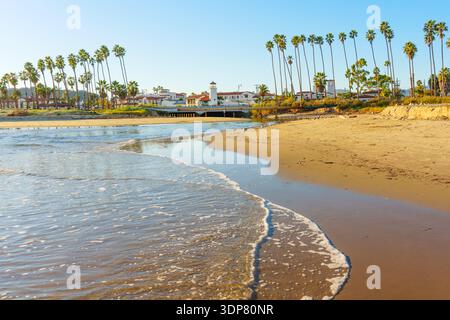 Santa Barbara, California - December 29, 2025: Winding beach estuary gently meeting the Pacific Ocean, framed by rows of palm trees and Spanish Coloni Stock Photo