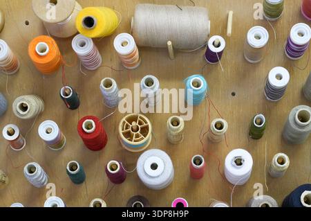 Colorful spools of thread for sewing on a wooden background. Stock Photo