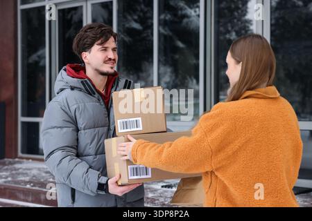 Woman receiving parcels from delivery man outdoors Stock Photo