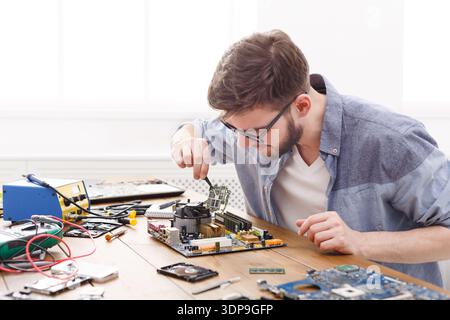 Tech Enthusiast Repairs Computer Motherboard in Bright Workspace During Daytime Hours Stock Photo