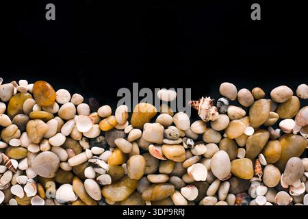 Seashells and pebbles on black background, natural seashore stones Stock Photo