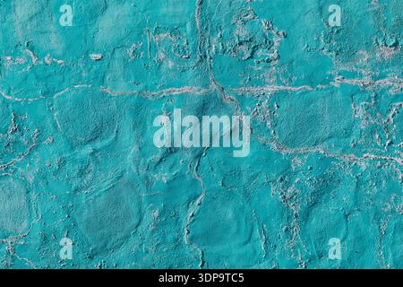 Textured wall painted in turquoise color, showing various shades and a slightly rough surface with visible cracks and uneven patches. Highly textured Stock Photo
