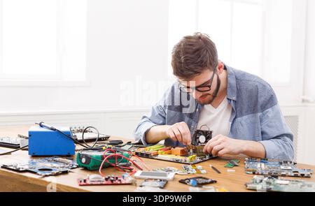 Technician Working on Computer Hardware in a Bright Room With Various Tools and Parts Present Stock Photo