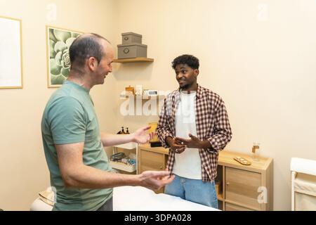 Two men engaging in a friendly and professional conversation about health and wellness, consulting with a specialist in a bright, modern clinic settin Stock Photo